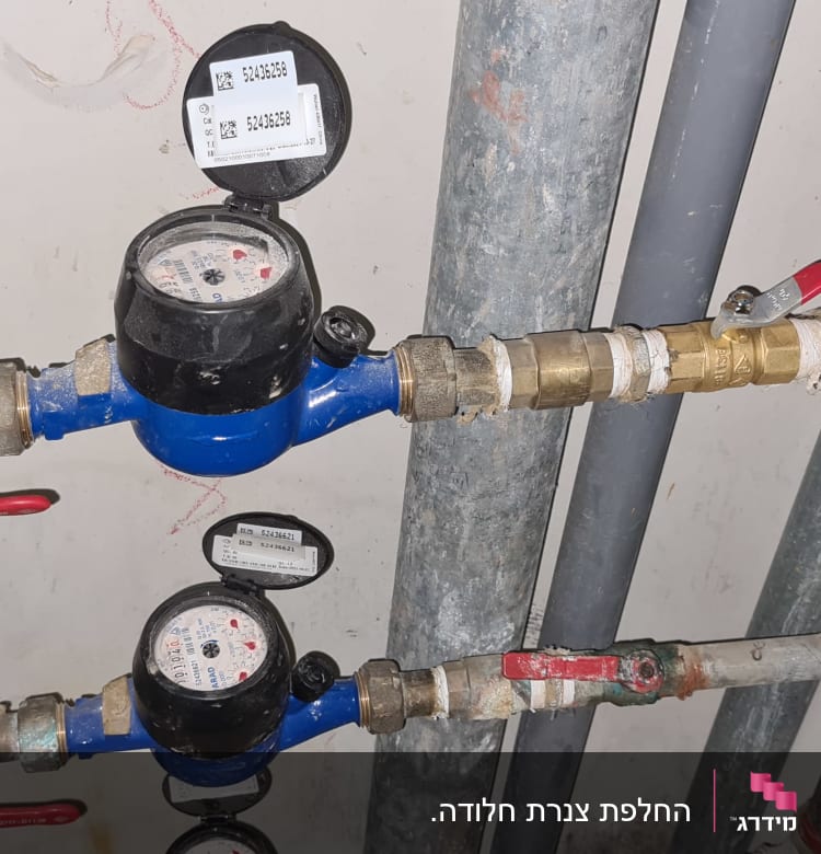 מד מים כחול עם ברזים אדומים וצינורות מתכת